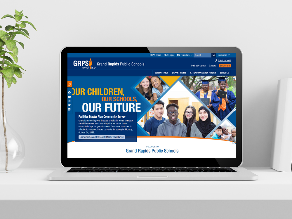 The new Grand Rapids Public Schools website homepage is displayed on a computer screen sitting on a desk.