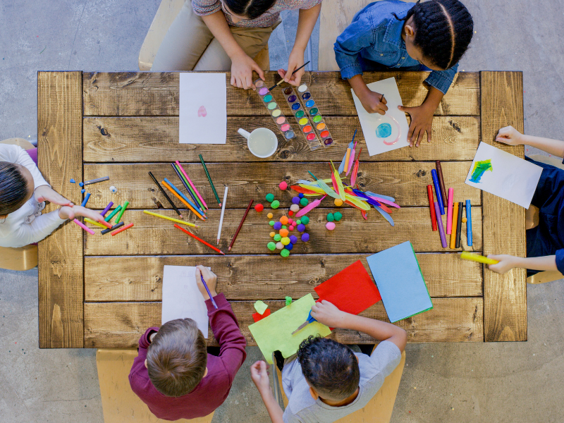 A group of 6 students sitting around the table doing arts and crafts